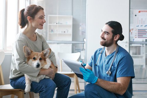 male-vet-filling-out-form-while-talking-with-pet-owner